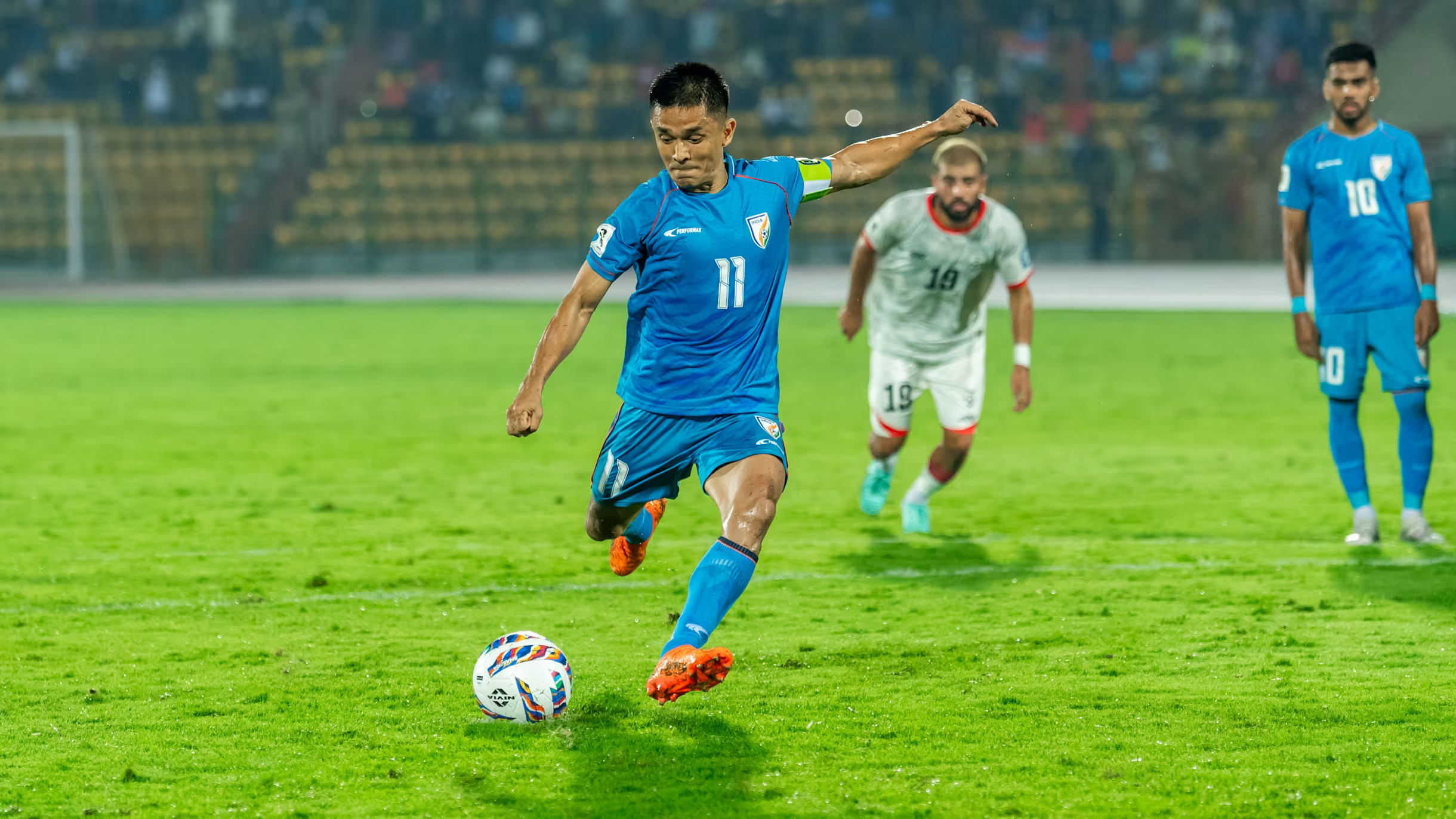 Sunil Chhetri wearing the blue Indian football team jersey taking a shot